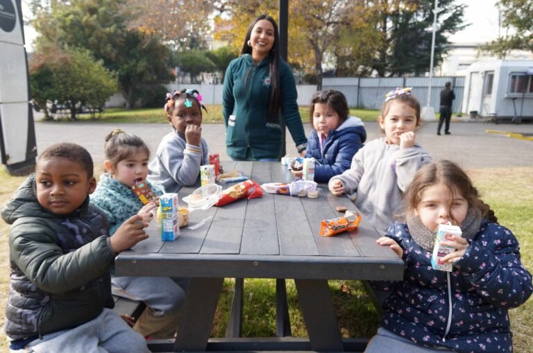 Niñas y niños de Pre-Kínder comparten la colación en una salida pedagógica junto a su educadora